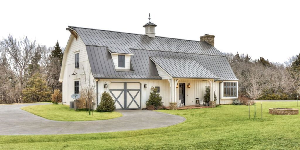 A farmhouse with a metal roof and a driveway.