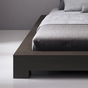 A bed with a wooden frame and a grey comforter.