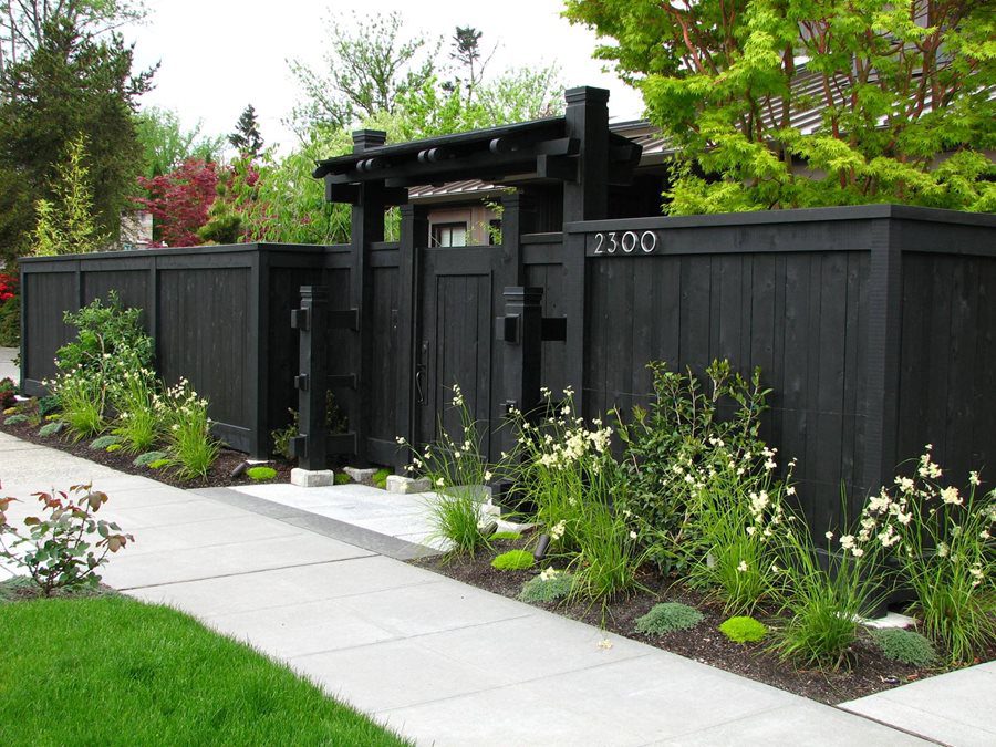 A black fence with a gate and a sidewalk.