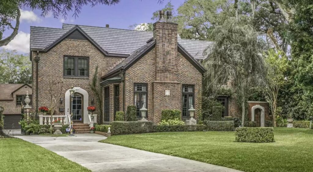 A brick home in the middle of a green lawn.